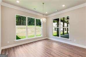 unfurnished dining area featuring ornamental molding, wood-type flooring, and a notable chandelier