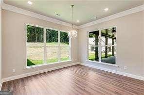 unfurnished dining area featuring crown molding, baseboards, wood finished floors, recessed lighting, and an inviting chandelier
