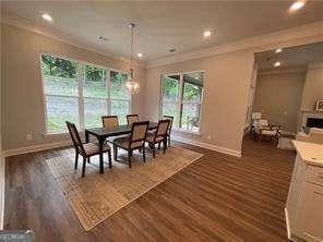 dining area featuring dark wood-type flooring, ornamental molding, baseboards, and a chandelier