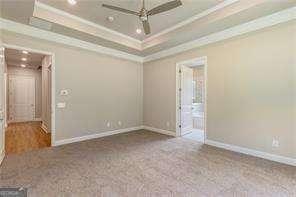 unfurnished room with crown molding, ceiling fan, a tray ceiling, and carpet