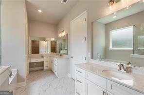full bathroom with vanity and a bath