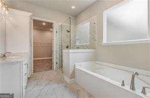 bathroom with shower with separate bathtub and vanity