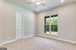 carpeted spare room with a ceiling fan and baseboards