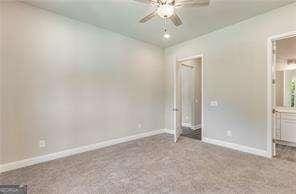 unfurnished bedroom featuring ceiling fan, carpet, and ensuite bath