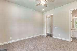 unfurnished bedroom featuring ensuite bath, carpet, baseboards, and ceiling fan