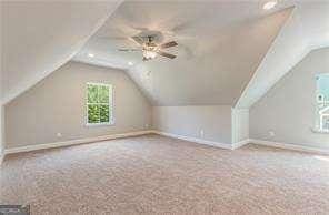 additional living space featuring ceiling fan, light colored carpet, and lofted ceiling