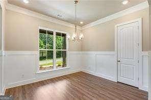 unfurnished dining area featuring dark wood-type flooring, crown molding, and a notable chandelier