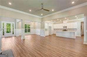 unfurnished living room featuring ceiling fan, ornamental molding, and hardwood / wood-style floors