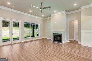 unfurnished living room featuring crown molding, ceiling fan, wood-type flooring, and french doors