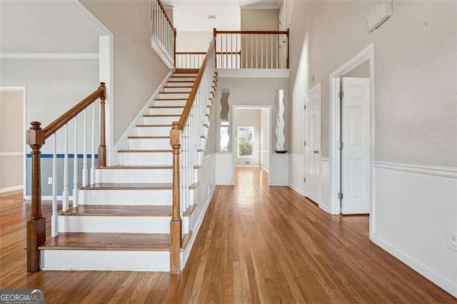 foyer entrance with hardwood / wood-style flooring, ornamental molding, and a high ceiling