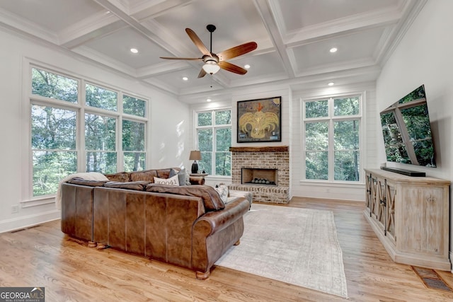 living room with coffered ceiling, a brick fireplace, light hardwood / wood-style flooring, ornamental molding, and beam ceiling