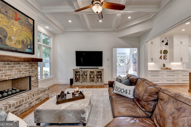 living room with beam ceiling, a brick fireplace, coffered ceiling, and light wood-type flooring