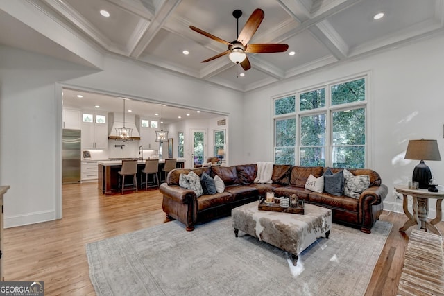 living room featuring coffered ceiling, a towering ceiling, beam ceiling, and light wood-type flooring