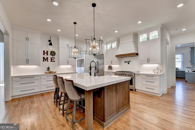 kitchen featuring white cabinetry, custom exhaust hood, high end appliances, hanging light fixtures, and a spacious island