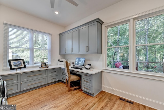 office featuring ceiling fan, built in desk, and light wood-type flooring