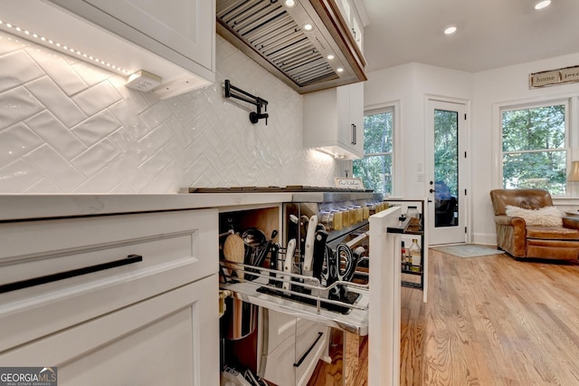 kitchen featuring white cabinetry, decorative backsplash, light hardwood / wood-style floors, and custom range hood