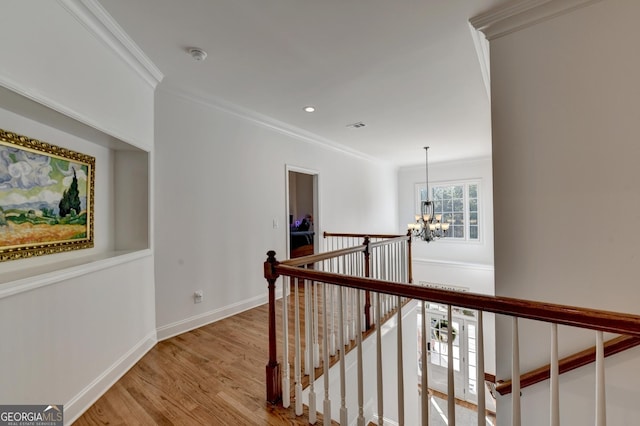 hallway featuring a notable chandelier, ornamental molding, and light hardwood / wood-style floors