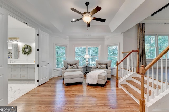 living area featuring ceiling fan, ornamental molding, a raised ceiling, and light hardwood / wood-style floors