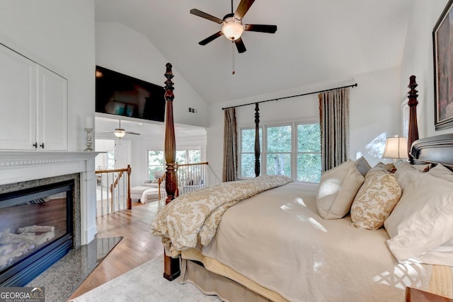 bedroom featuring ceiling fan, high vaulted ceiling, a fireplace, and hardwood / wood-style floors