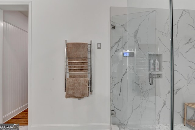 bathroom featuring radiator heating unit, a shower with door, and wood-type flooring