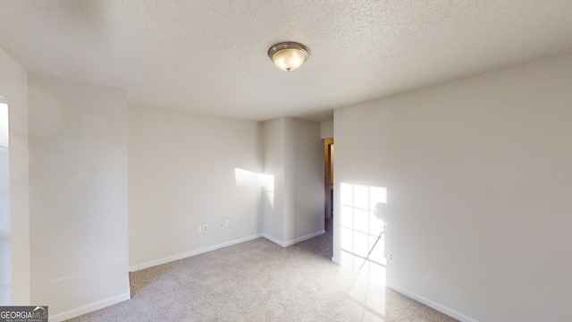 unfurnished room with light colored carpet and a textured ceiling