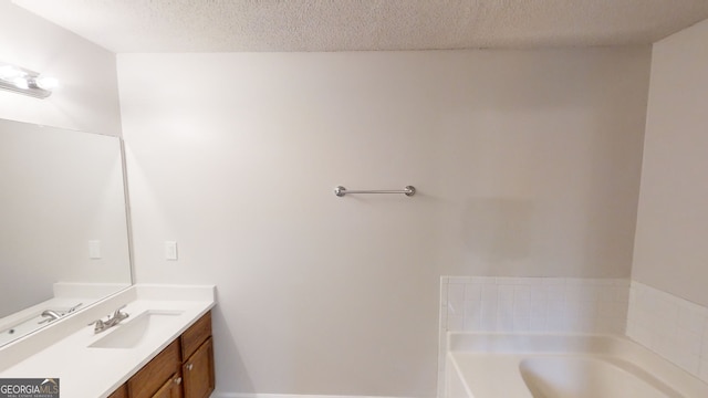 bathroom featuring vanity, a bath, and a textured ceiling