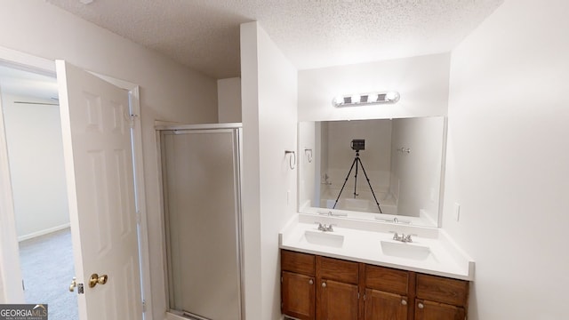 bathroom with vanity, a shower with door, and a textured ceiling