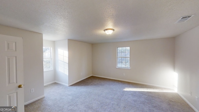 unfurnished room with light colored carpet and a textured ceiling