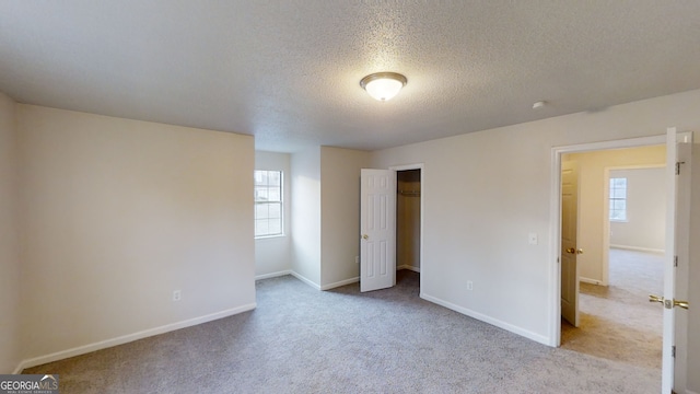 unfurnished bedroom featuring light colored carpet, a closet, and a textured ceiling