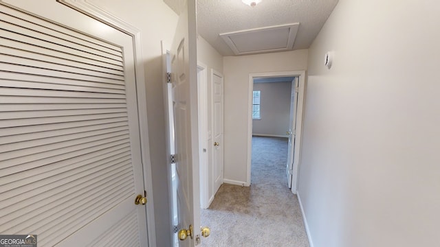 corridor featuring light carpet and a textured ceiling