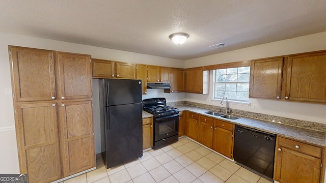 kitchen with light tile patterned floors, sink, a textured ceiling, and black appliances