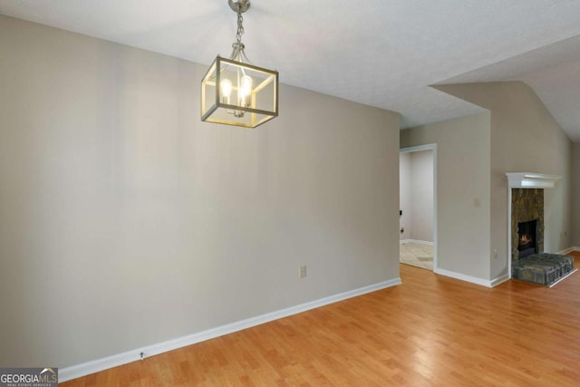 interior space with hardwood / wood-style flooring, lofted ceiling, a chandelier, and a fireplace