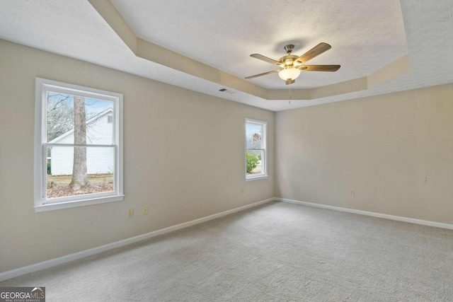 carpeted empty room with ceiling fan, a raised ceiling, and a textured ceiling