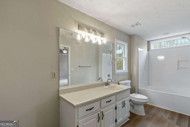 full bathroom with shower / bath combination, hardwood / wood-style floors, vanity, a textured ceiling, and toilet