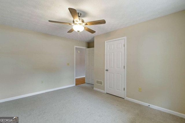 unfurnished bedroom featuring ceiling fan, light colored carpet, and a textured ceiling