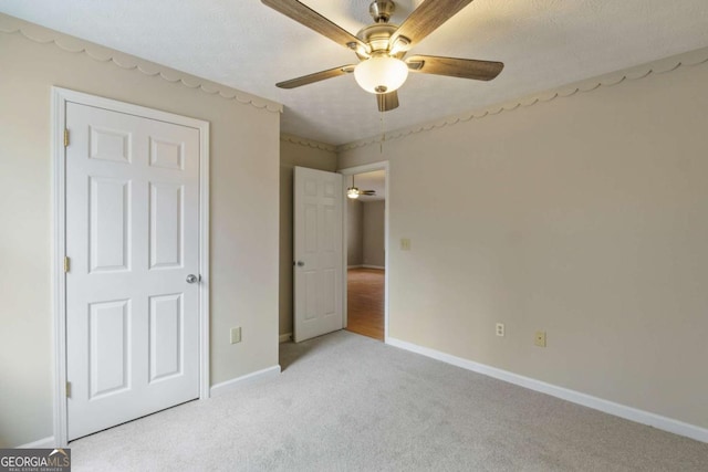 unfurnished bedroom with ceiling fan, light colored carpet, and a textured ceiling