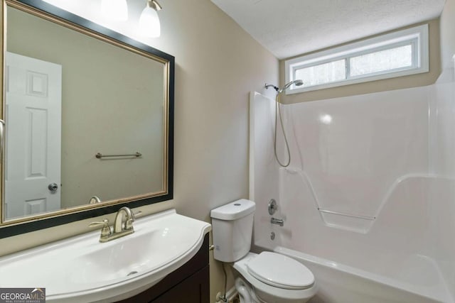 full bathroom with vanity, toilet,  shower combination, and a textured ceiling