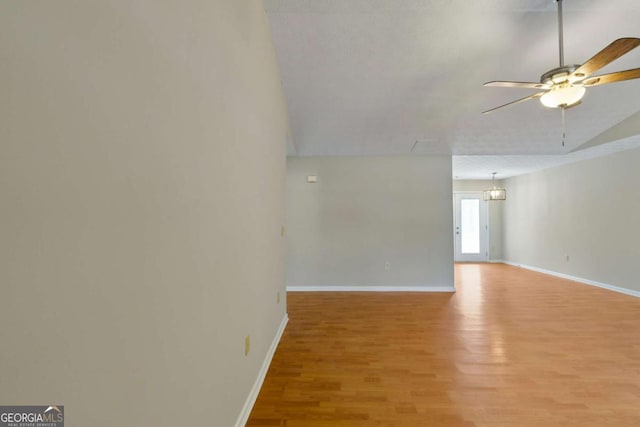 empty room with lofted ceiling, ceiling fan, and light wood-type flooring