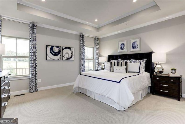 carpeted bedroom with crown molding and a tray ceiling