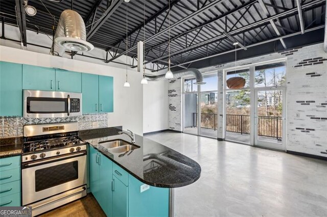 kitchen with sink, dark stone countertops, appliances with stainless steel finishes, kitchen peninsula, and decorative backsplash