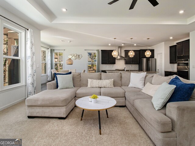 carpeted living room featuring a tray ceiling and ceiling fan