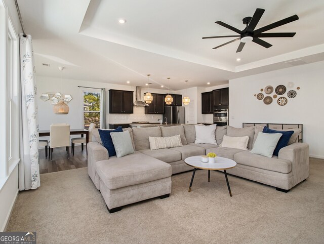 living room with ceiling fan, light hardwood / wood-style floors, and a tray ceiling