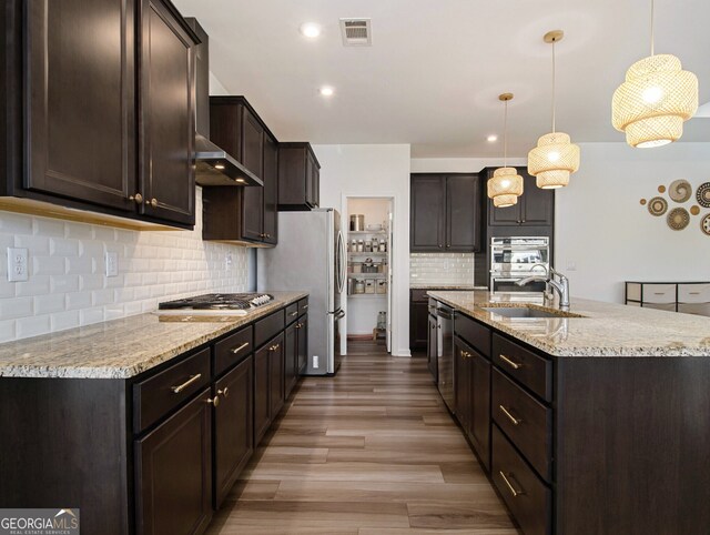 kitchen with sink, dark brown cabinets, hanging light fixtures, and appliances with stainless steel finishes