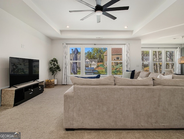 living room featuring carpet, ceiling fan, and a tray ceiling