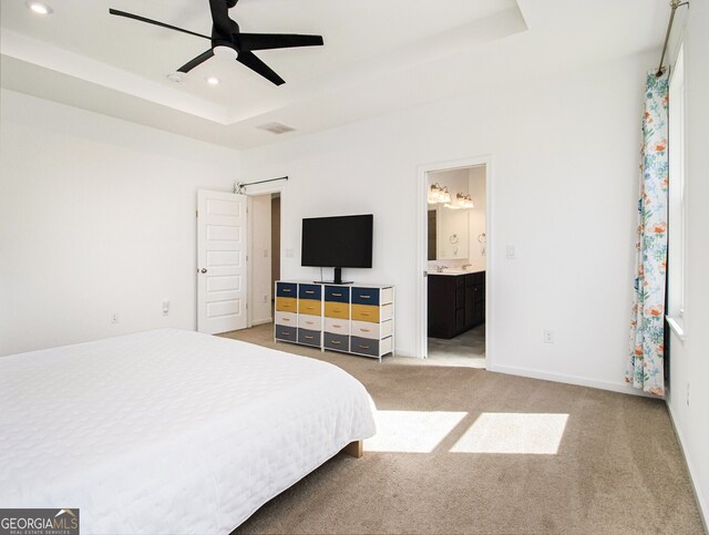 bedroom featuring ensuite bathroom, carpet flooring, ceiling fan, and a tray ceiling