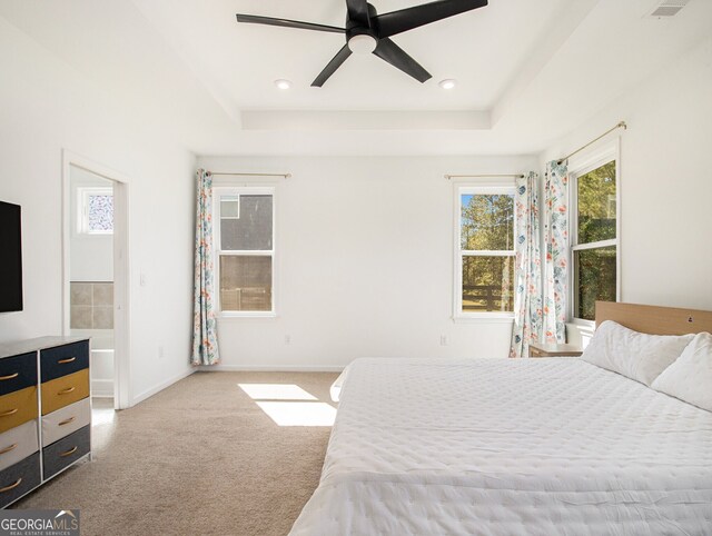 carpeted bedroom featuring a raised ceiling and ceiling fan