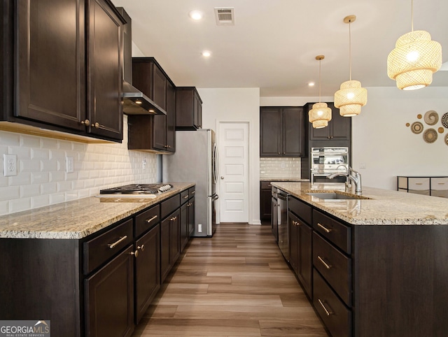 kitchen featuring dark brown cabinetry, sink, wood-type flooring, decorative light fixtures, and stainless steel appliances