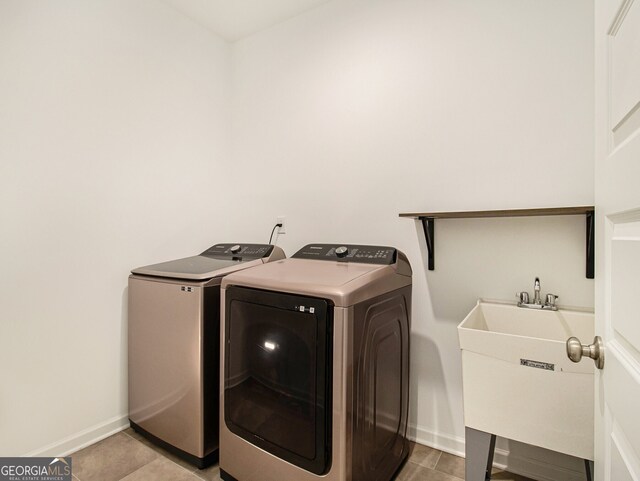 laundry room featuring sink, washer and dryer, and light tile patterned flooring