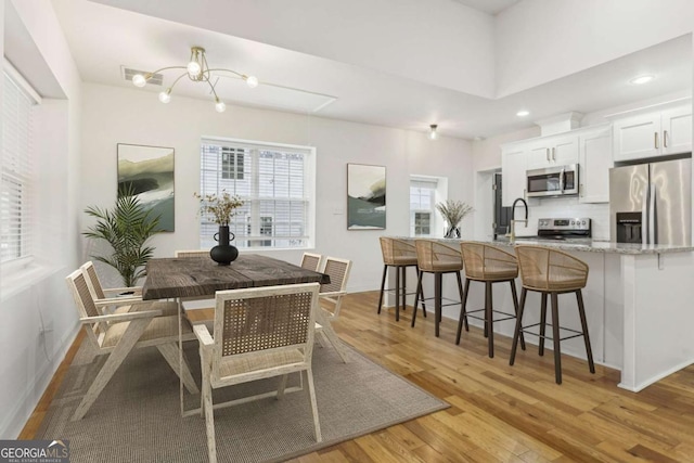 dining space featuring an inviting chandelier and light wood-type flooring