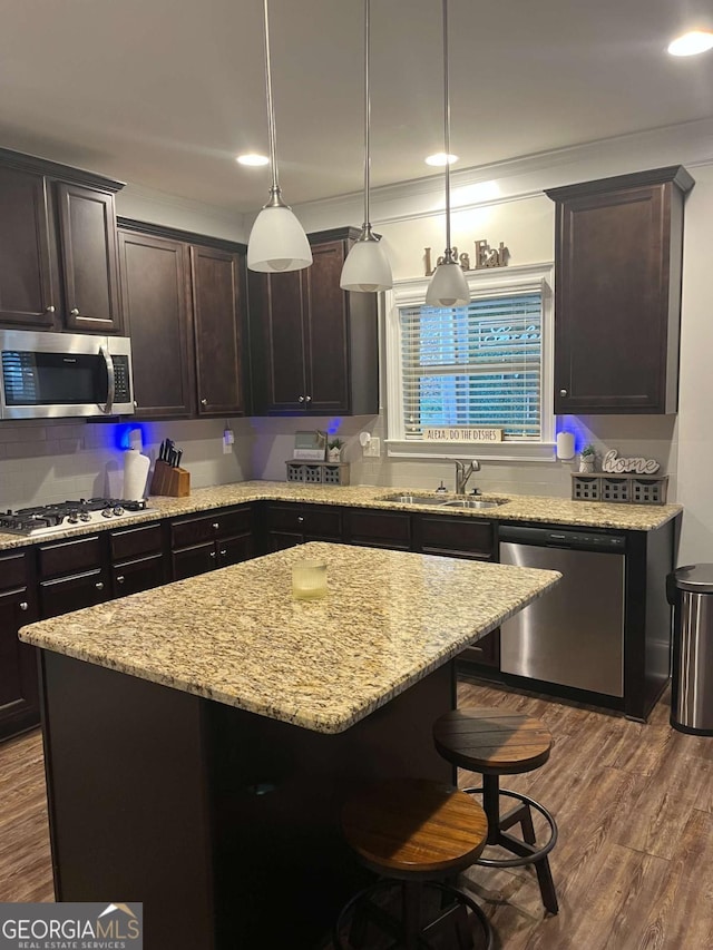 kitchen with appliances with stainless steel finishes, a center island, sink, and dark brown cabinets